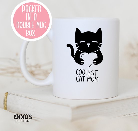 Witte mok met zwarte print van een kat die een hart vasthoudt met de tekst "COOLEST CAT MOM". Ronde roze sticker met "PACKED IN A DOUBLE MUG BOX".