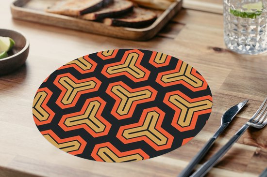 Set de table rond avec un motif géométrique noir, doré et orange sur une table.