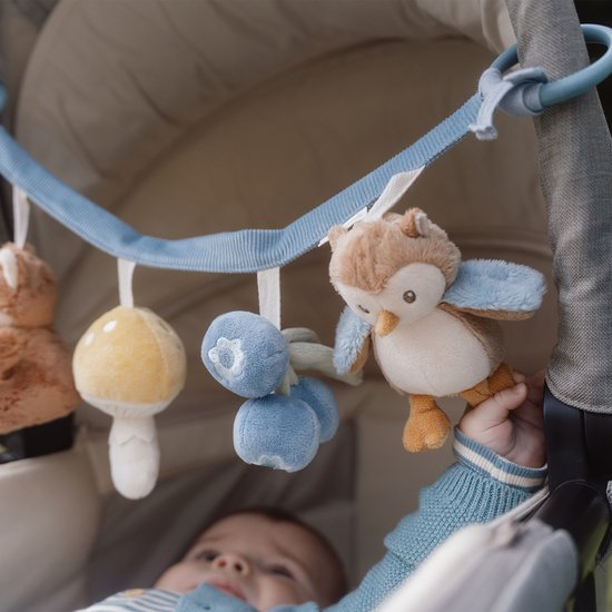 Baby speelt met kinderwagenhanger met vos, paddenstoel, bosbessen en uil.