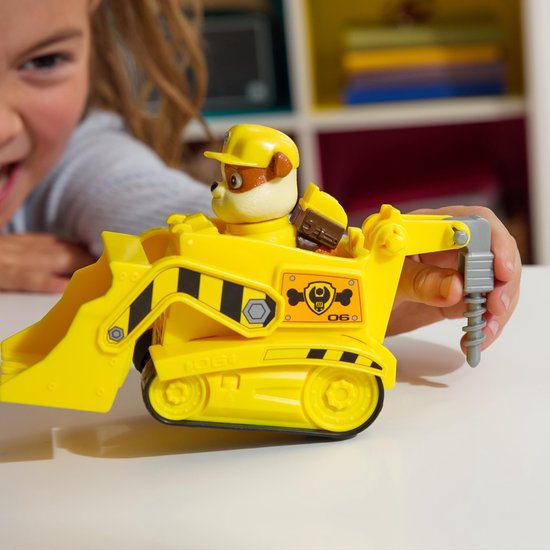 Kind speelt met de gele Paw Patrol bulldozer speelgoed met Rubble, die de boor bedient.