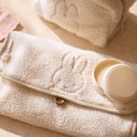 Gedetailleerde close-up van een crèmekleurige teddy verschoonmat met beige rand, houten knoopje en geborduurd Nijntje.