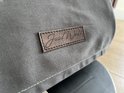 Detail van grijze stof met bruin "Jaxx World" label.