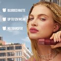 Vrouw met bruin getinte lippenstift en tekst: "BLURRED MATTE, UP TO 12H WEAR, NO TRANSFER".