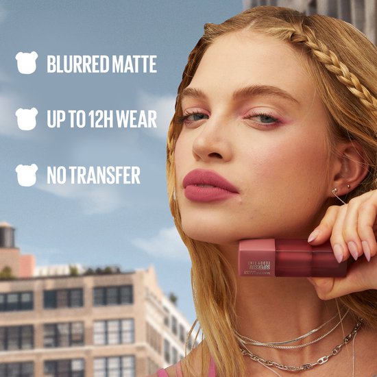 Vrouw met bruin getinte lippenstift en tekst: "BLURRED MATTE, UP TO 12H WEAR, NO TRANSFER".