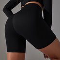 Close-up van de achterkant van een model in een zwarte biker short met textuur en naden.