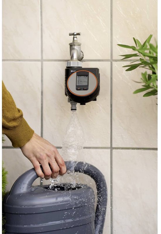 Gardena digitale timer met scherm, aangesloten op een waterkraan. Vult een grijze gieter met water.