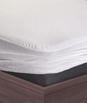 Close-up van een witte, zachte matrasbeschermer met elastiek, passend op een matras.