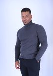 Man in een donkergrijs coltrui en zwarte broek.