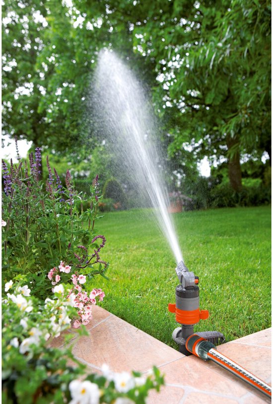 GARDENA turbinesproeier in gebruik, sproeit water op een groen gazon naast bloemen