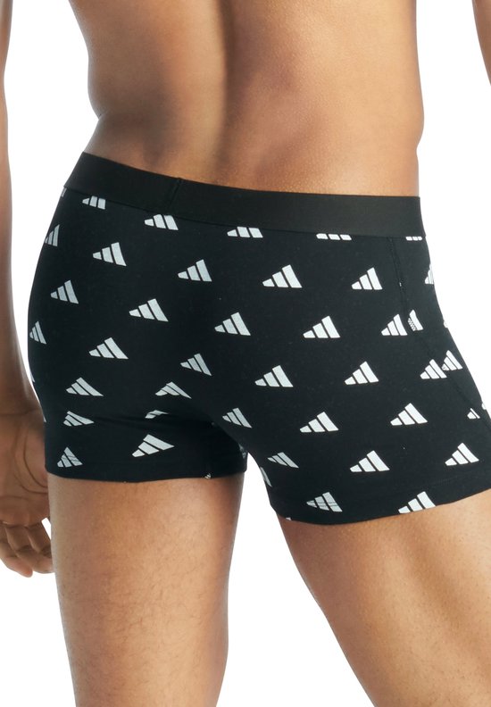Zijkant van een man met een zwarte Adidas boxershort met witte logo's.