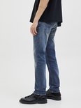 Zijaanzicht van de benen van een man in een zwart T-shirt en blauwe jeans.