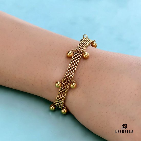 Gouden mesh armband met hangende balletjes gedragen op een arm.