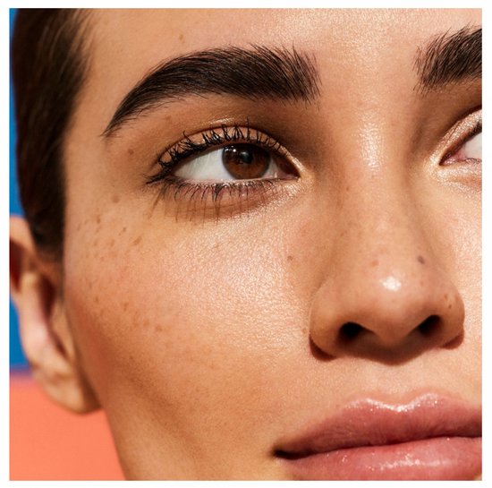Close-up van een gezicht met sproeten en glanzende huid, met de Nuxe Huile Prodigieuse multi-purpose dry oil.