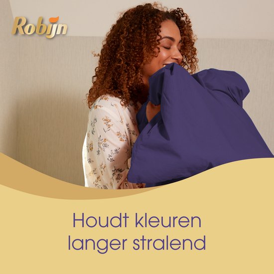 Vrouw met krullend haar die een paars laken ruikt, "Houdt kleuren langer stralend".