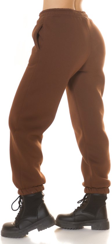 Zijzicht van een bruine joggingbroek met hoge taille, gedragen met zwarte laarzen.