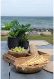 Houten tafel met groene planten, houten fruitschaal met druiven en brood.