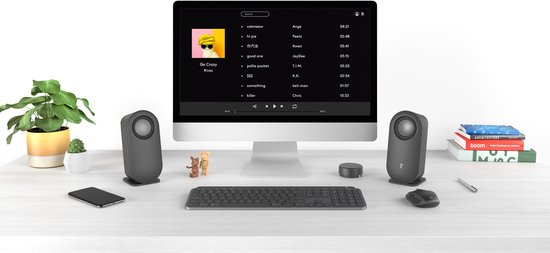 Opstelling met een computer, twee grijze speakers, een volumeknop, toetsenbord, muis en een smartphone.