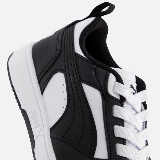 Close-up van de zijkant van een zwart-witte sneaker met witte veters en stiksels.