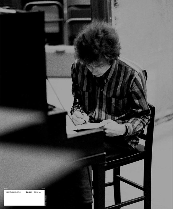 Jonge man met krullend haar, gekleed in een gestreept shirt, schrijft in een boek.
