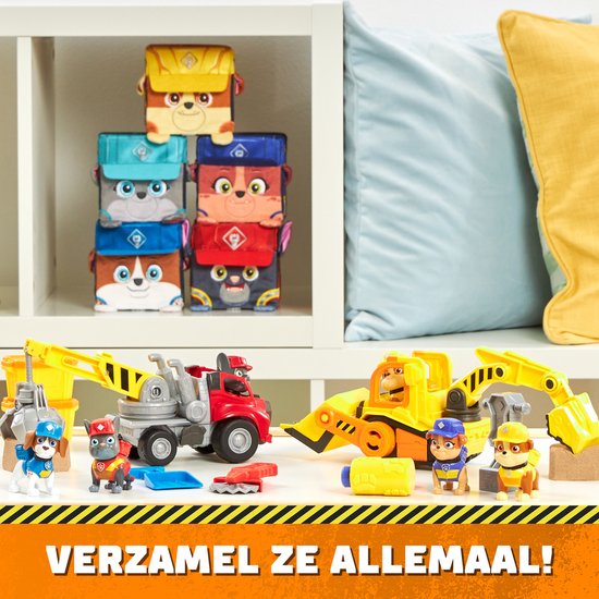 Verschillende Rubble & Crew speelgoedvoertuigen op een tafel, waaronder een blauwe kiepwagen.