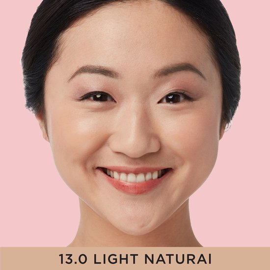 Model met een glimlach, met op de huid de IT Cosmetics concealer in de kleur 13.0 Light Natural.