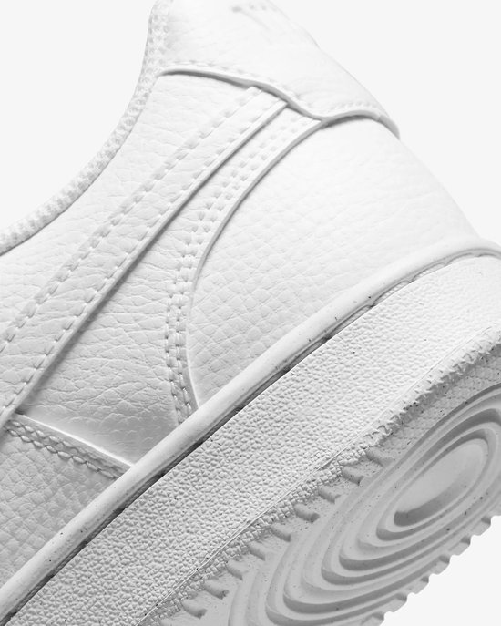 Close-up van de zijkant en zool van een witte Nike sneaker met getextureerd leer.