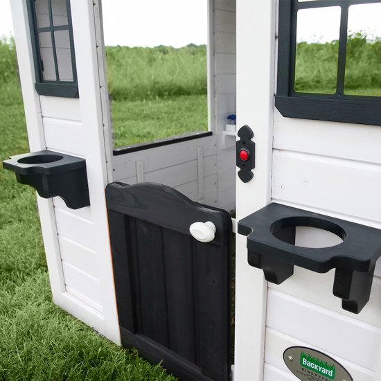 Detail van de entree van het witte speelhuis met zwarte deur, postbus en speelgoedschalen.