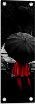 WallClassics - Tuinposter – Vrouw in Rood bij Zwarte Auto met Paraplu - 20x60 cm Foto op Tuinposter (wanddecoratie voor buiten en binnen)