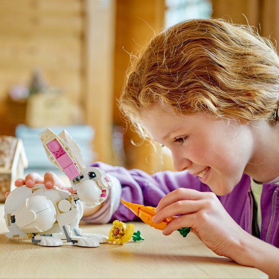 Une fille joue avec un lapin LEGO blanc et une carotte.