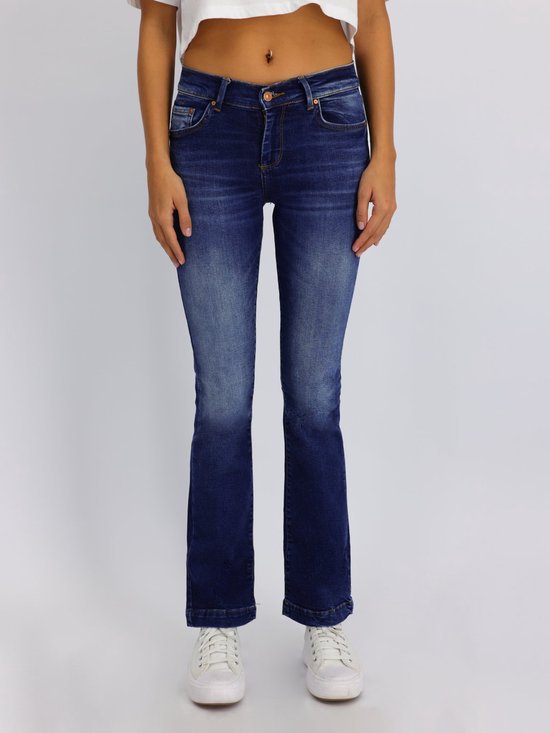 Model draagt een donkerblauwe flared jeans met lichte wassing, voorkant.