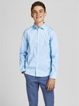 Un garçon porte une chemise bleu clair à manches longues et un pantalon bleu.