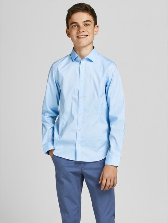 Un garçon porte une chemise bleu clair à manches longues et un pantalon bleu.
