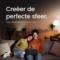 Stelpaar op een bank kijkt samen naar een laptop in een gezellig verlichte woonkamer.