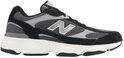 Zwarte New Balance sneaker met grijze mesh en suède details, witte zool en zilveren 'N' logo.