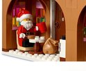 LEGO Kerstman in zijn peperkoekhuisje, zittend aan een tafel met een mok en koekjes, met een zak ernaast.