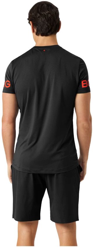 Man in zwart sportshirt en short, met rode tekst op de mouwen.