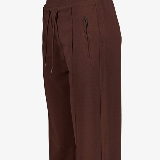 Detailopname van een donkerbruine broek met trekkoord, ritszak en pintuck-details.