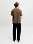 Achteraanzicht van een model in een bruin t-shirt en zwarte broek.