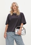 Model draagt donkergrijs T-shirt met stierkop, zilveren ketting en tas.