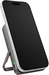 Witte smartphone op een donkergrijze magnetische powerbank met ingebouwde standaard in een schuine positie.