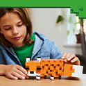 Garçon construisant un renard LEGO orange avec des taches brunes et des accents blancs.