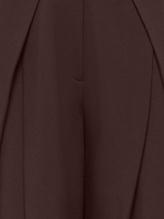 Detail van de stof en plooien van de donkerbruine broek.