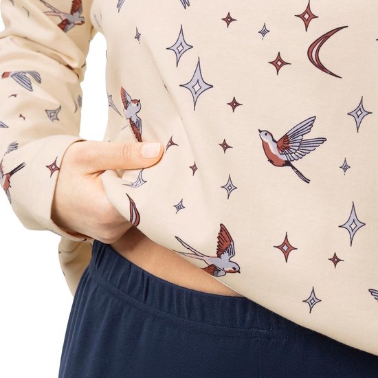 Close-up van crème pyjamatop met gedetailleerde vogel- en sterrenprint.