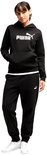Model in een zwarte Puma hoodie en bijpassende joggingbroek, met de hand in de zak van de hoodie.