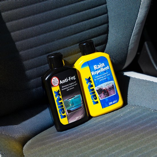 Zwarte Anti-Fog fles en gele Rain Repellent fles van Rain-X op een autostoel.