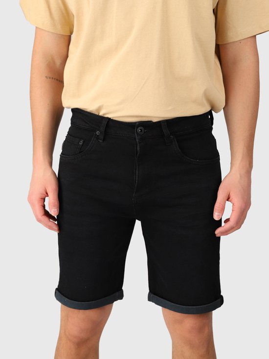Close-up van de voorkant van zwarte denim shorts met een knoopsluiting, gedragen met een beige T-shirt.