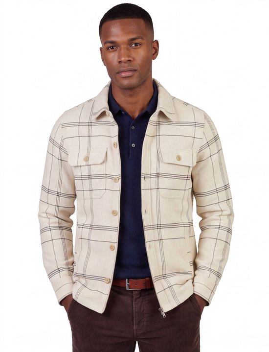 Model draagt een beige overshirt met zwart ruitpatroon en knoopsluiting over een donkerblauw poloshirt.