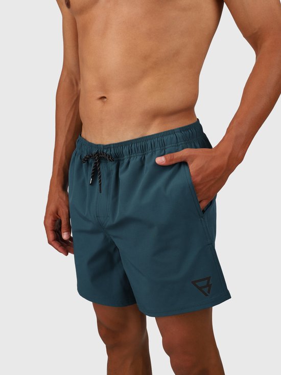 Homme portant un maillot de bain vert Fuel. Le maillot de bain a un cordon de serrage et un logo sur la jambe gauche.