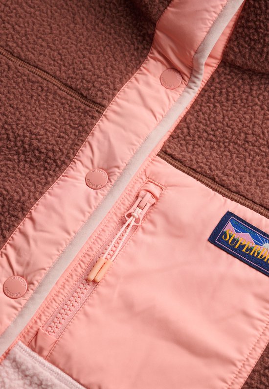 Close-up van de roze drukknoopsluiting en ritsvak van een bruine fleece jas.