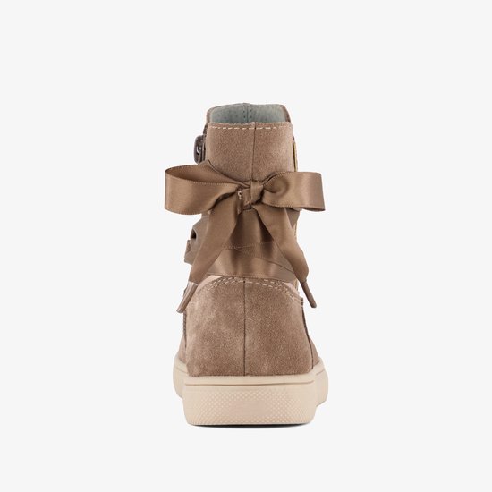 Achterkant van beige suède enkellaarsjes met een grote strik aan de bovenzijde.